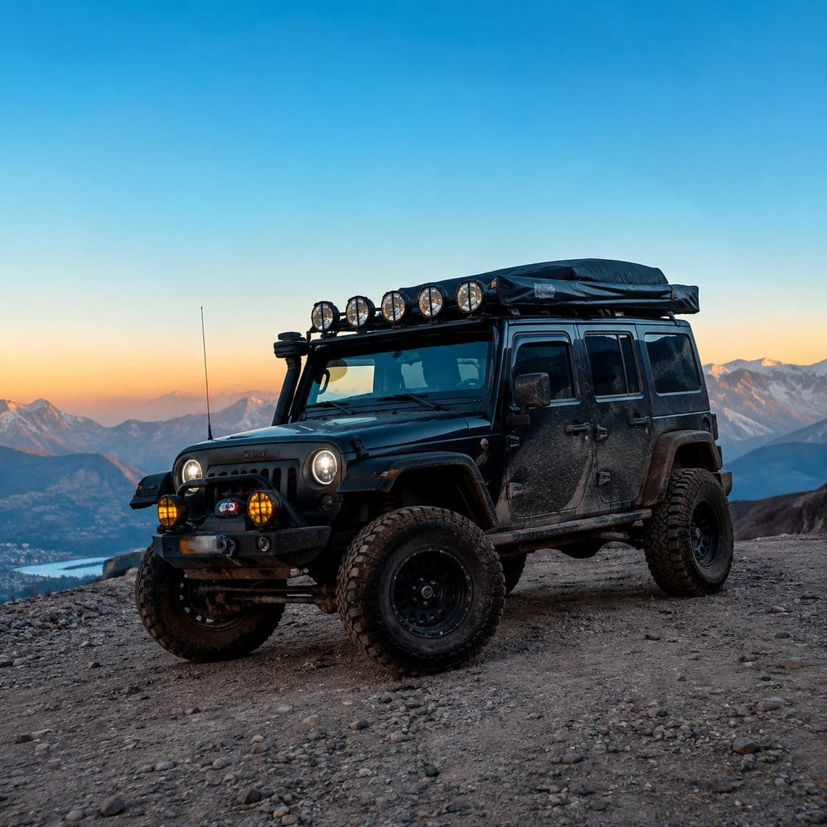 Off-road jeep parked on a mountain ridge at sunset