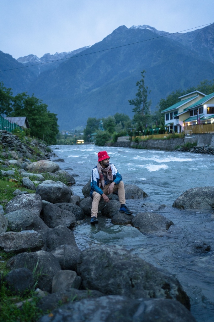 Traveller sitting on rocks by a mountain river